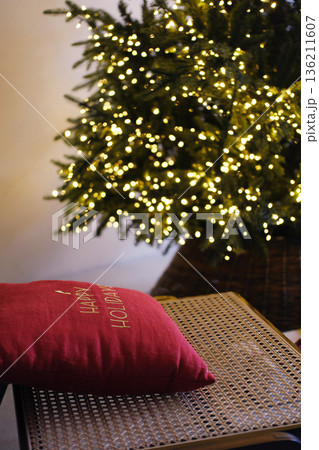 Cozy Christmas living room decor featuring a minimalist Scandinavian style with a beautifully lit tree and a festive pillow, creating a warm holiday atmosphere with copy space Cozy Christmas living room decor featuring a minimalist Scandinavian style with a beautifully lit tree and a festive pillow, creating a warm holiday atmosphere with copy space 136211607