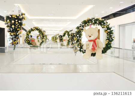 Christmas decorations featuring festive wreaths and plush teddy bears in a modern shopping center, creating a joyful holiday atmosphere with vibrant colors and cheerful ambiance 136211613