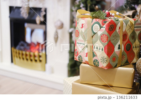 Colorful Christmas gift boxes with decorative patterns are placed beside a cozy fireplace, creating a warm and festive atmosphere for holiday celebrations Colorful Christmas gift boxes with decorative patterns are placed beside a cozy fireplace, creating a warm and festive atmosphere for holiday celebrations 136211633