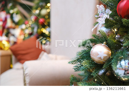 Christmas tree adorned with golden ornaments and festive decorations, creating a warm and inviting atmosphere in a cozy living room setting with soft lighting 136211661