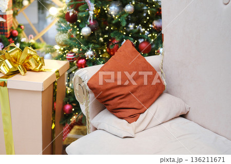 Cozy living room corner with plush pillows and a beautifully decorated Christmas tree, adorned with lights and ornaments, creating a festive holiday atmosphere Cozy living room corner with plush pillows and a beautifully decorated Christmas tree, adorned with lights and ornaments, creating a festive holiday atmosphere 136211671
