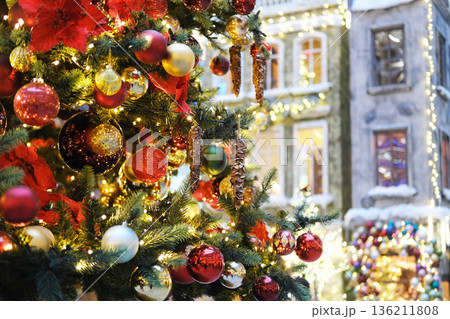 Christmas tree adorned with colorful ornaments and twinkling lights in a festive shopping mall, creating a joyful atmosphere for holiday celebrations and New Year festivities Christmas tree adorned with colorful ornaments and twinkling lights in a festive shopping mall, creating a joyful atmosphere for holiday celebrations and New Year festivities 136211808