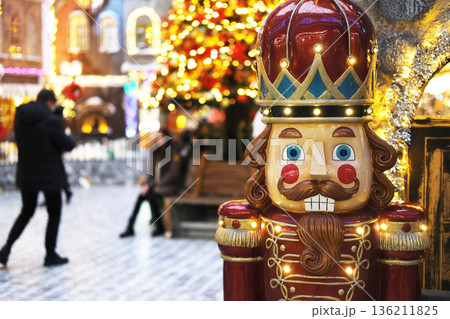Colorful nutcracker decoration stands in a festive shopping mall adorned with bright lights and Christmas trees, creating a joyful holiday atmosphere for shoppers and visitors 136211825