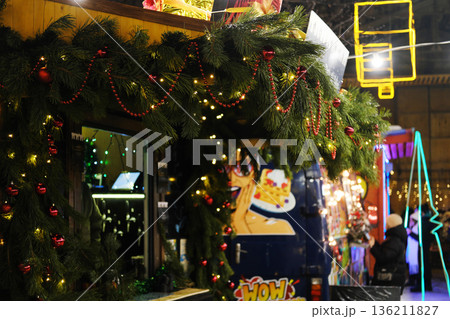 Festive holiday market scene featuring decorated food stall adorned with greenery, lights, and ornaments, creating a warm and inviting atmosphere for seasonal celebrations 136211827