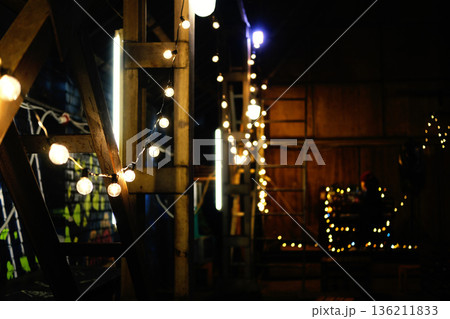 Warm, glowing string lights illuminate rustic wooden beams in a cozy indoor space, creating a festive atmosphere perfect for holiday gatherings and celebrations 136211833