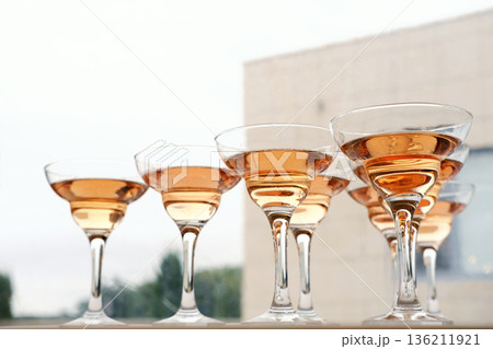 Elegant champagne glasses filled with sparkling rose wine are arranged in a row, showcasing the delicate hues and reflections, perfect for celebrations and toasting moments Elegant champagne glasses filled with sparkling rose wine are arranged in a row, showcasing the delicate hues and reflections, perfect for celebrations and toasting moments 136211921