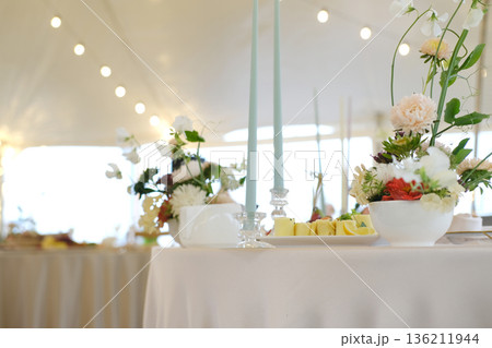 Elegant wedding table setting featuring floral arrangements, soft candlelight, and gourmet dishes, creating a romantic atmosphere for a memorable celebration 136211944