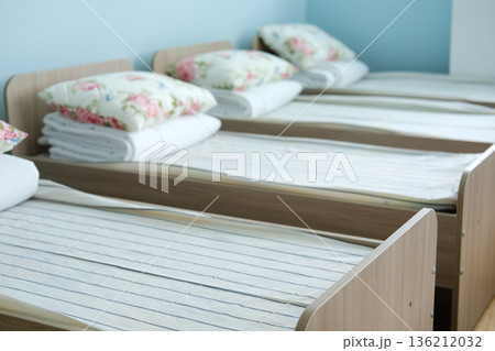 Empty sleeping area in kindergarten with neatly arranged beds and soft pillows, featuring a calm atmosphere and ample copy space for text or design elements 136212032