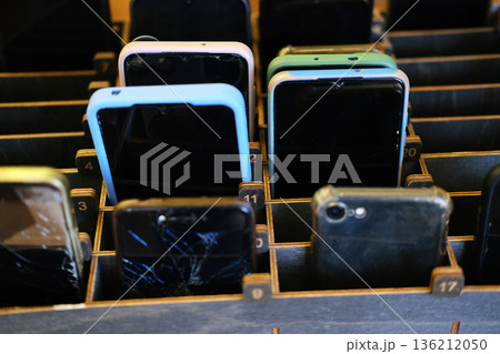 Collection of various smartphones arranged in wooden display, showcasing different colors and conditions, highlighting technology and mobile device diversity with copy space 136212050