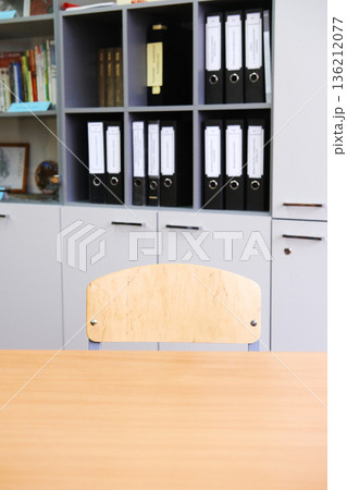 School desk and chair positioned opposite a cabinet filled with organized folders, creating a minimalist study environment with copy space for design purposes School desk and chair positioned opposite a cabinet filled with organized folders, creating a minimalist study environment with copy space for design purposes 136212077