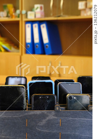 Students' cell phones stored in a wooden box, showcasing a school environment where mobile devices are prohibited, emphasizing focus on learning and classroom engagement Students' cell phones stored in a wooden box, showcasing a school environment where mobile devices are prohibited, emphasizing focus on learning and classroom engagement 136212079