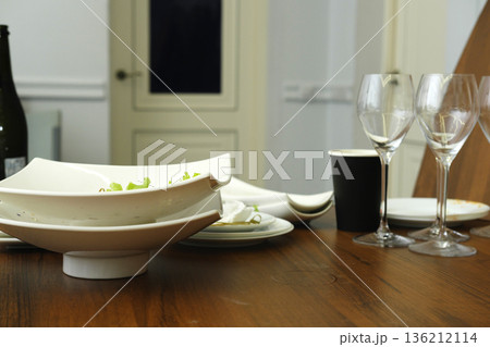 Elegant dining table setting featuring white ceramic bowls, wine glasses, and a black cup, creating a sophisticated atmosphere for a meal or gathering Elegant dining table setting featuring white ceramic bowls, wine glasses, and a black cup, creating a sophisticated atmosphere for a meal or gathering 136212114