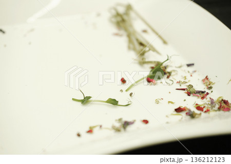 Leftover food remnants on a white plate, featuring scattered herbs and colorful flower petals, illustrating the concept of food waste and its environmental impact Leftover food remnants on a white plate, featuring scattered herbs and colorful flower petals, illustrating the concept of food waste and its environmental impact 136212123