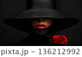 Elegant female model in retro hat with red lips and rose flower against a dark background 136212992