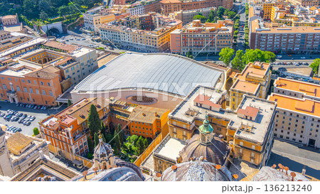 Visitors are enjoying the architecture of Paul VI Hall in Vatican City. The large hall features a glass roof and surrounding buildings. The scene captures the essence of this historic location. Visitors are enjoying the architecture of Paul VI Hall in Vatican City. The large hall features a glass roof and surrounding buildings. The scene captures the essence of this historic location. 136213240