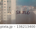 Handwritten Spanish language message Lo siento is Sorry on misted glass on sunset window 136213400