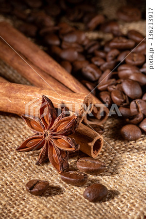 Close-up of scattered coffee beans, star anise, and cinnamon on burlap napkin Close-up of scattered coffee beans, star anise, and cinnamon on burlap napkin 136213917