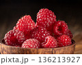 Close-up of a rustic wooden cup filled with fresh raspberries on a wooden table 136213927