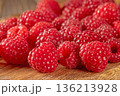 Close-up of fresh ripe raspberries scattered on a rustic table surface 136213928
