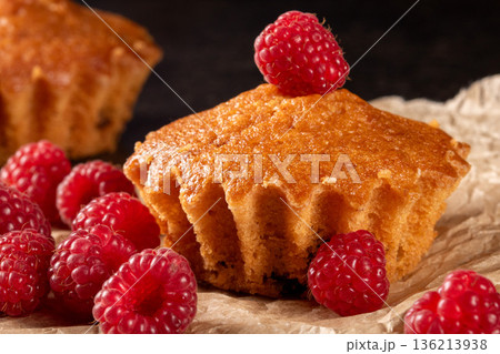 Lemon muffins surrounded by juicy raspberries on a cozy kitchen table scene 136213938