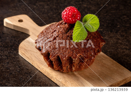 Close-up of a decorated raspberry muffin on a wooden cutting board Close-up of a decorated raspberry muffin on a wooden cutting board 136213939