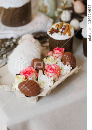 Chocolate Easter eggs with roses and bunny in carton on festive spring table, soft bokeh 136214695