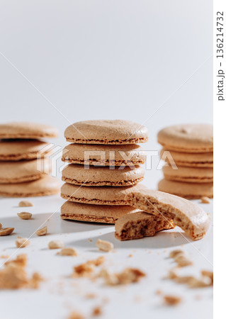 Stacked peanut macarons with bitten cookie and crumbs on white background Stacked peanut macarons with bitten cookie and crumbs on white background 136214732