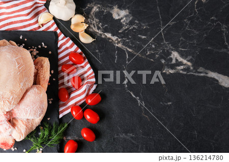 Top view of whole frozen chicken with cherry tomatoes, garlic and dill on black marble background. Raw poultry meat ingredients with copy space for text. High quality photo Top view of whole frozen chicken with cherry tomatoes, garlic and dill on black marble background. Raw poultry meat ingredients with copy space for text. High quality photo 136214780