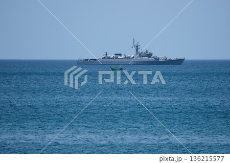 view through palm trees on a warship of the Thai Armed Forces stands in sea at sunny day 136215577