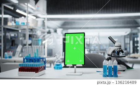 Green screen tablet on laboratory workbench next to microscope and liquid samples. Close up of mockup device on research station prepared for analyzing experimental data from chemical solution tests Green screen tablet on laboratory workbench next to microscope and liquid samples. Close up of mockup device on research station prepared for analyzing experimental data from chemical solution tests 136216489