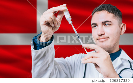 Doctor holding syringe on Denmark flag background. Medical professional holding syringe with Danish flag in the background Doctor holding syringe on Denmark flag background. Medical professional holding syringe with Danish flag in the background 136217329