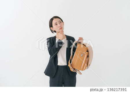 ランドセルを持って考える表情の女性 136217391
