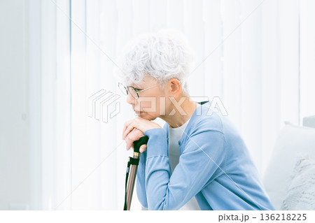 リビングで杖を手に落ち込むシニア女性 リビングで杖を手に落ち込むシニア女性 136218225