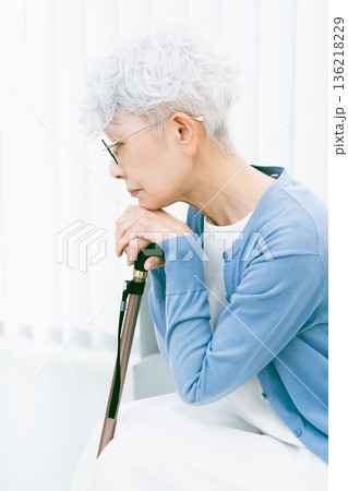 リビングで杖を手に落ち込むシニア女性 136218229