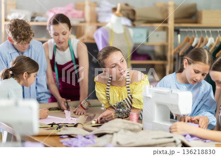 Sewing lesson - a group of teenage children learn to sew on sewing machine and cut fabric 136218830