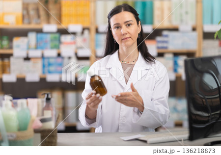 Female pharmacist offering cough syrup Female pharmacist offering cough syrup 136218873