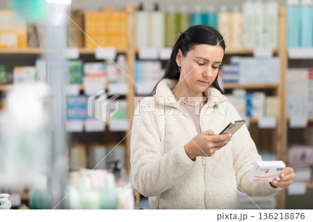 Middle-aged woman customer scanning QR-code on paracetamol box 136218876