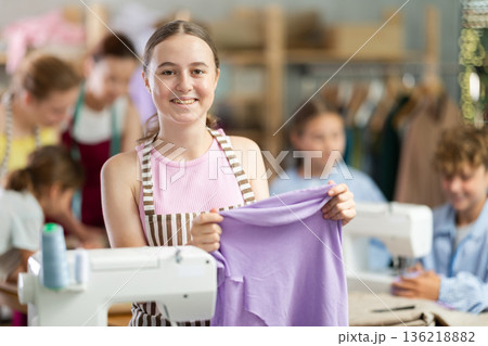Teenage girl shows fabric she sewed with her own hands during sewing class Teenage girl shows fabric she sewed with her own hands during sewing class 136218882