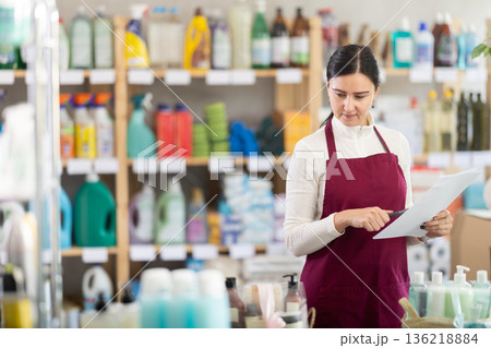 saleswoman writes down on paper the amount of the remaining goods in the warehouse saleswoman writes down on paper the amount of the remaining goods in the warehouse 136218884