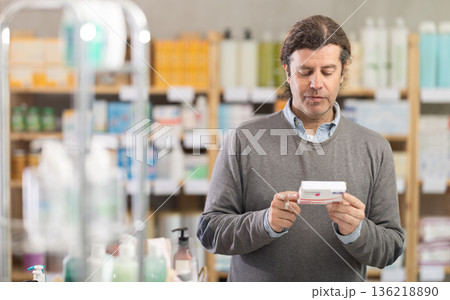 In drug store, man examine paracetamol antipyretic pills 136218890