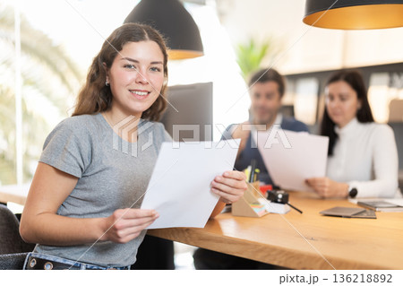 Young woman manager sitting at the stand against the background of customers 136218892