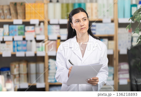 Female pharmacist filling out papers in pharmacy Female pharmacist filling out papers in pharmacy 136218893