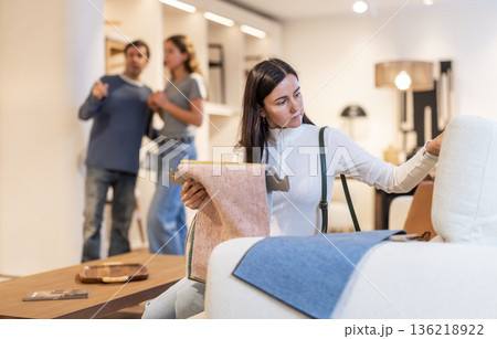 European woman looks at upholstery fabric in a store 136218922