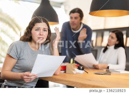 Upset female manager with papers in front of clients Upset female manager with papers in front of clients 136218923