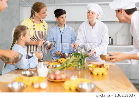 Team of positive teenagers and female chef at cooking classes. Learn to beat raw eggs 136219037