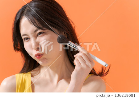 メイクブラシを持つ明るい女性 136219081