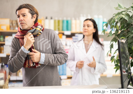 Man with sore throat and cough choosing pills with help from pharmacist 136219115