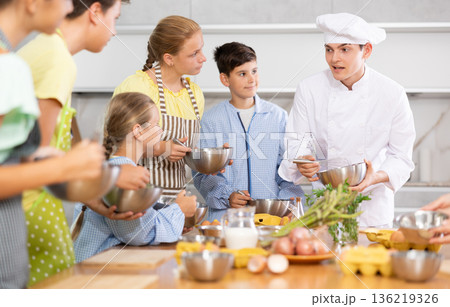 Friendly young chef running culinary courses for group of children 136219326