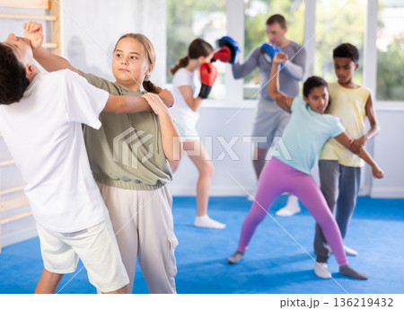 Teenage girl performing palm strike to chin in self-defense sparring with boy Teenage girl performing palm strike to chin in self-defense sparring with boy 136219432