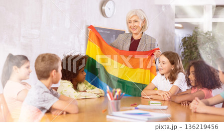 Female teacher showing rainbow flag to kids in geography class 136219456